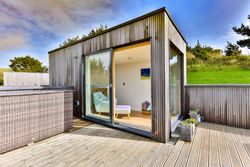 Modern wooden garden room with large sliding glass doors and deck