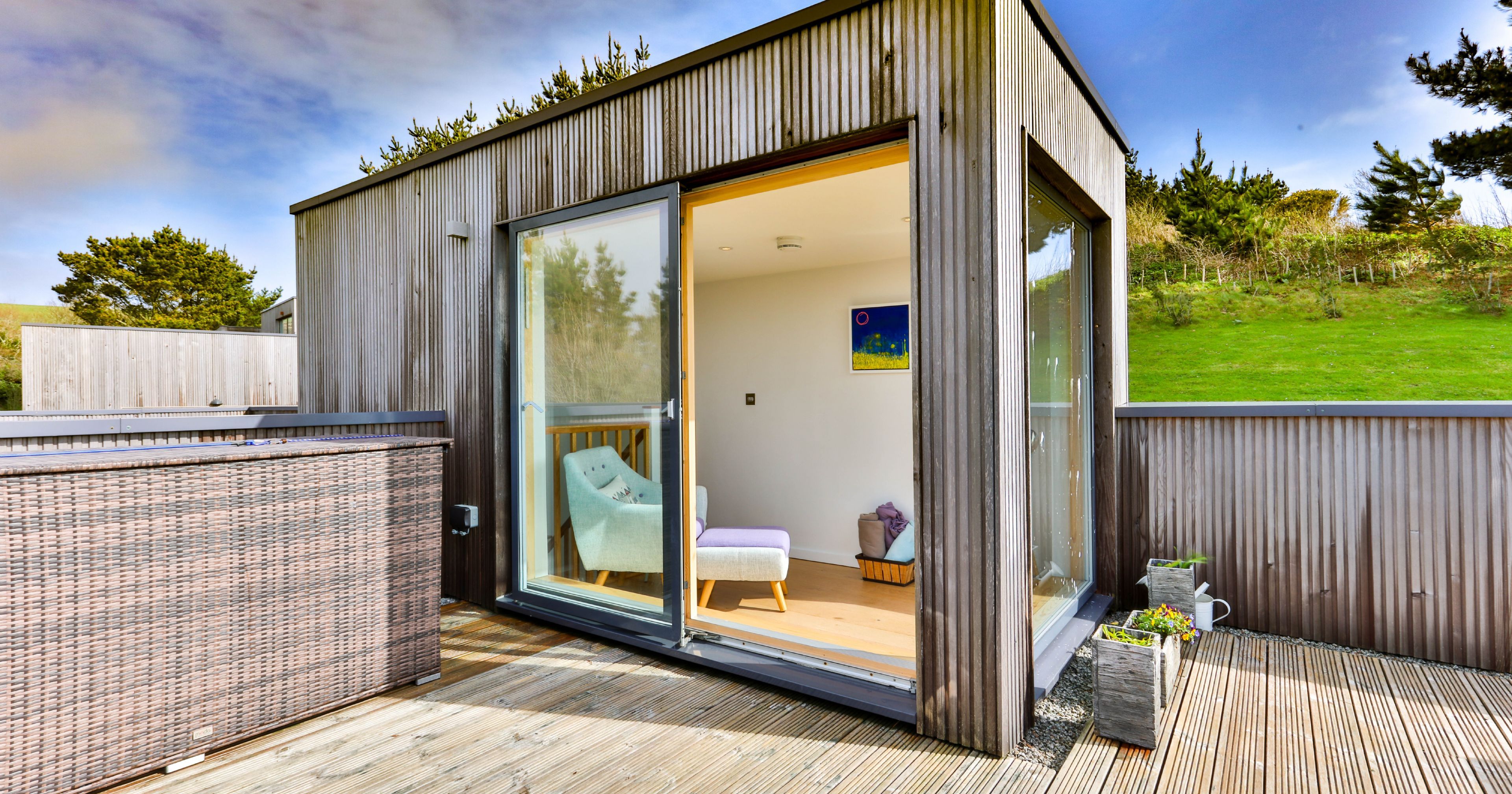 Modern wooden garden room with large sliding glass doors and deck