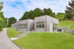 Modern single-story building with wooden cladding set on a grassy hillside