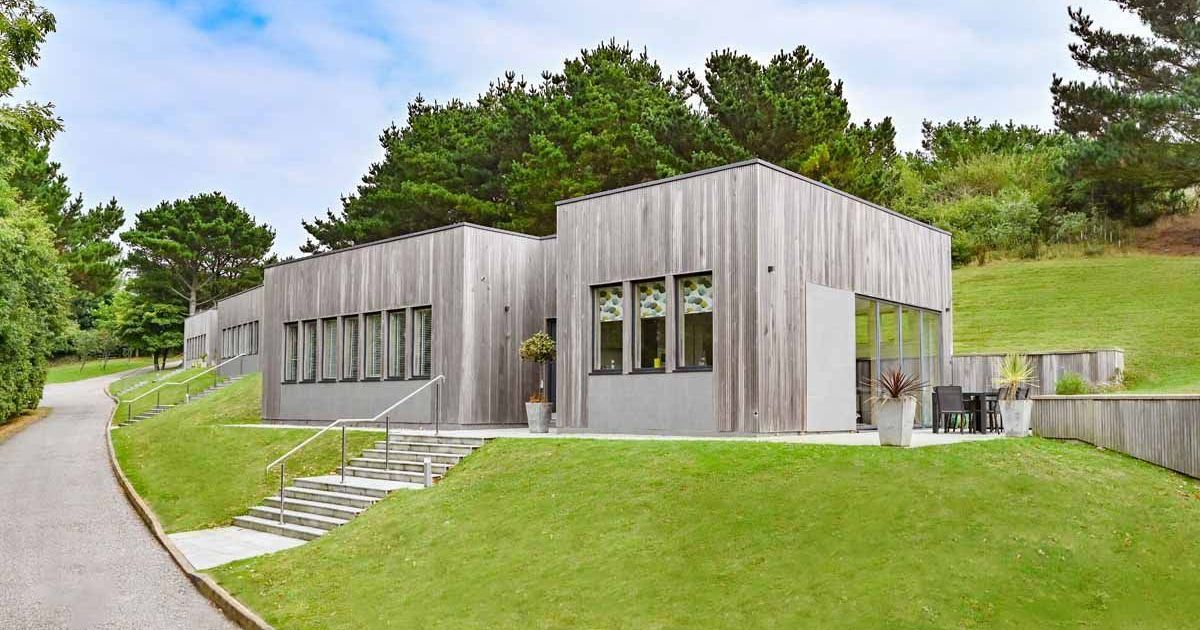 Modern single-story building with wooden cladding set on a grassy hillside