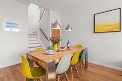 Modern dining room with wooden table, colorful chairs, and pendant lights