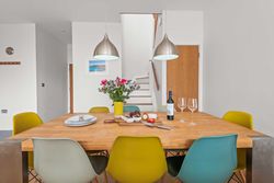 Modern dining room with wooden table, colorful chairs, and pendant lights