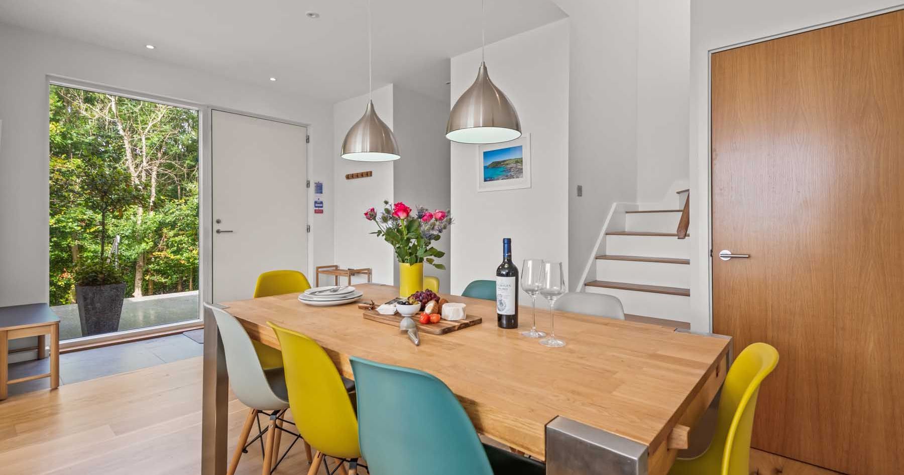 Modern dining room with colorful chairs, wooden table, and pendant lights