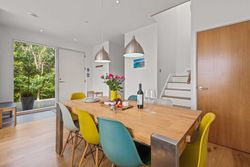 Modern dining room with colorful chairs, wooden table, and pendant lights