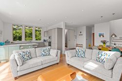 Modern open plan living room and kitchen with large windows and contemporary furniture.