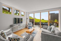 Modern living room with large windows overlooking a green garden and outdoor dining area.