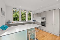 Modern kitchen with white countertops, light grey cabinets, and large windows.