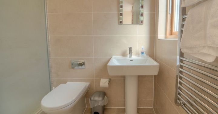 Modern bathroom with toilet, sink, mirror, and towel rack
