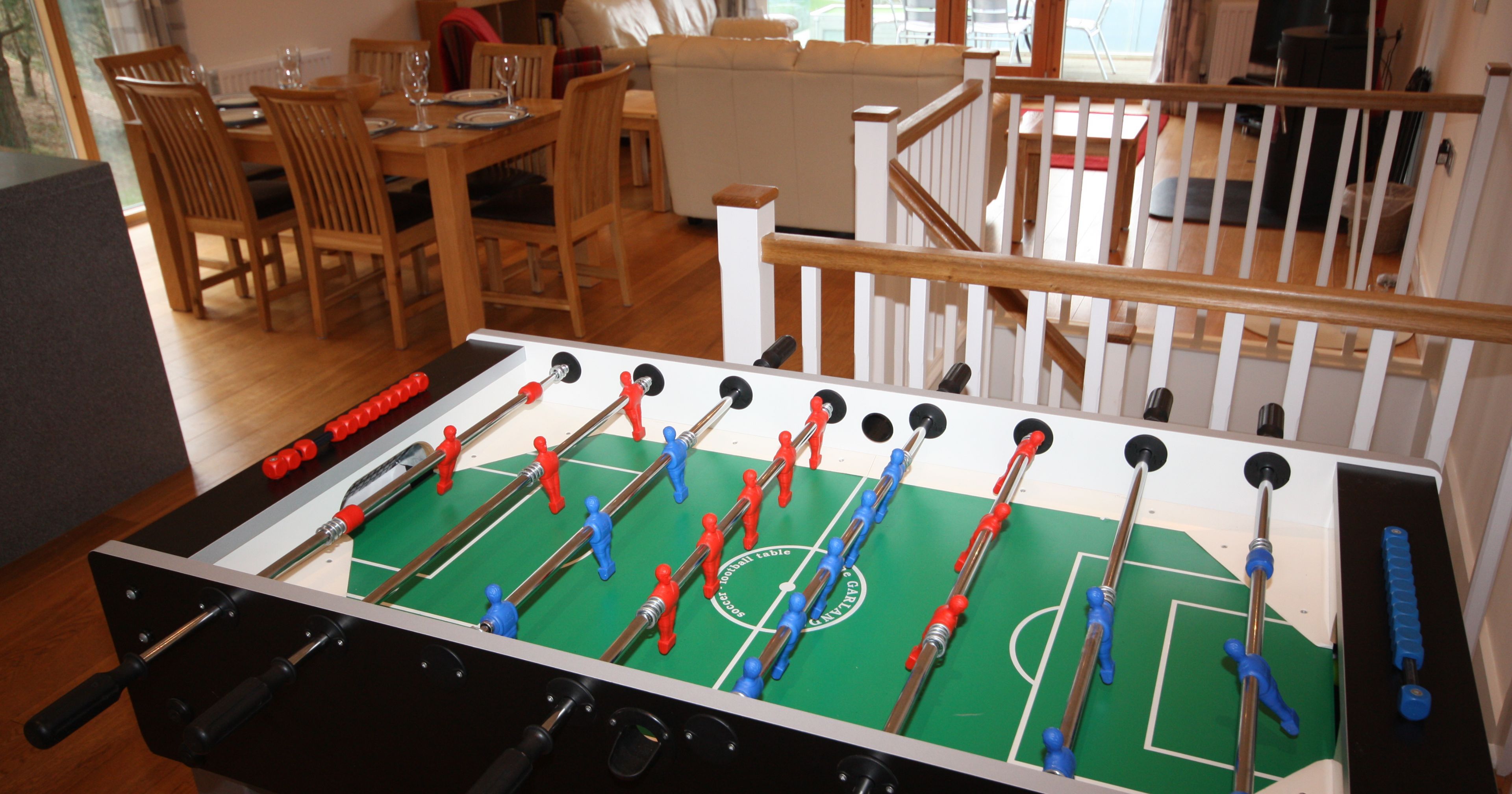 Foosball table in a modern living room with dining area in the background