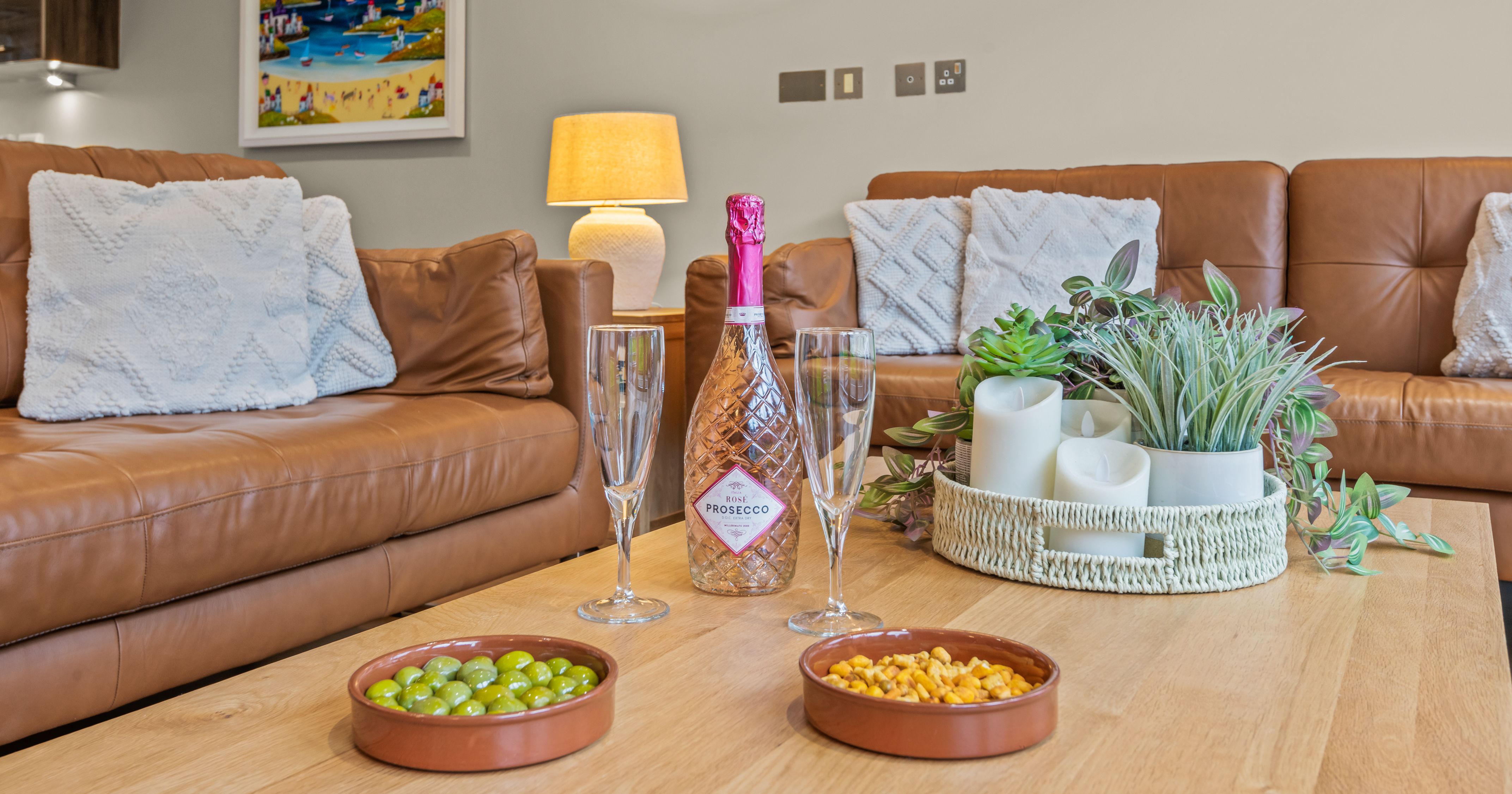 Coffee table setting with prosecco, glasses, snacks, and candles in a cozy living room