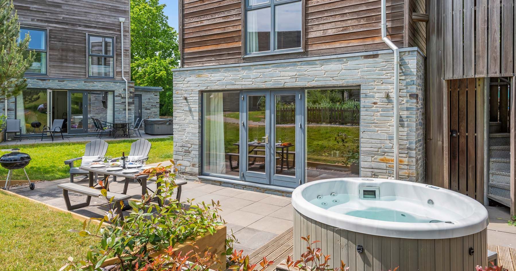 Modern house with patio, hot tub, outdoor dining area, and barbecue