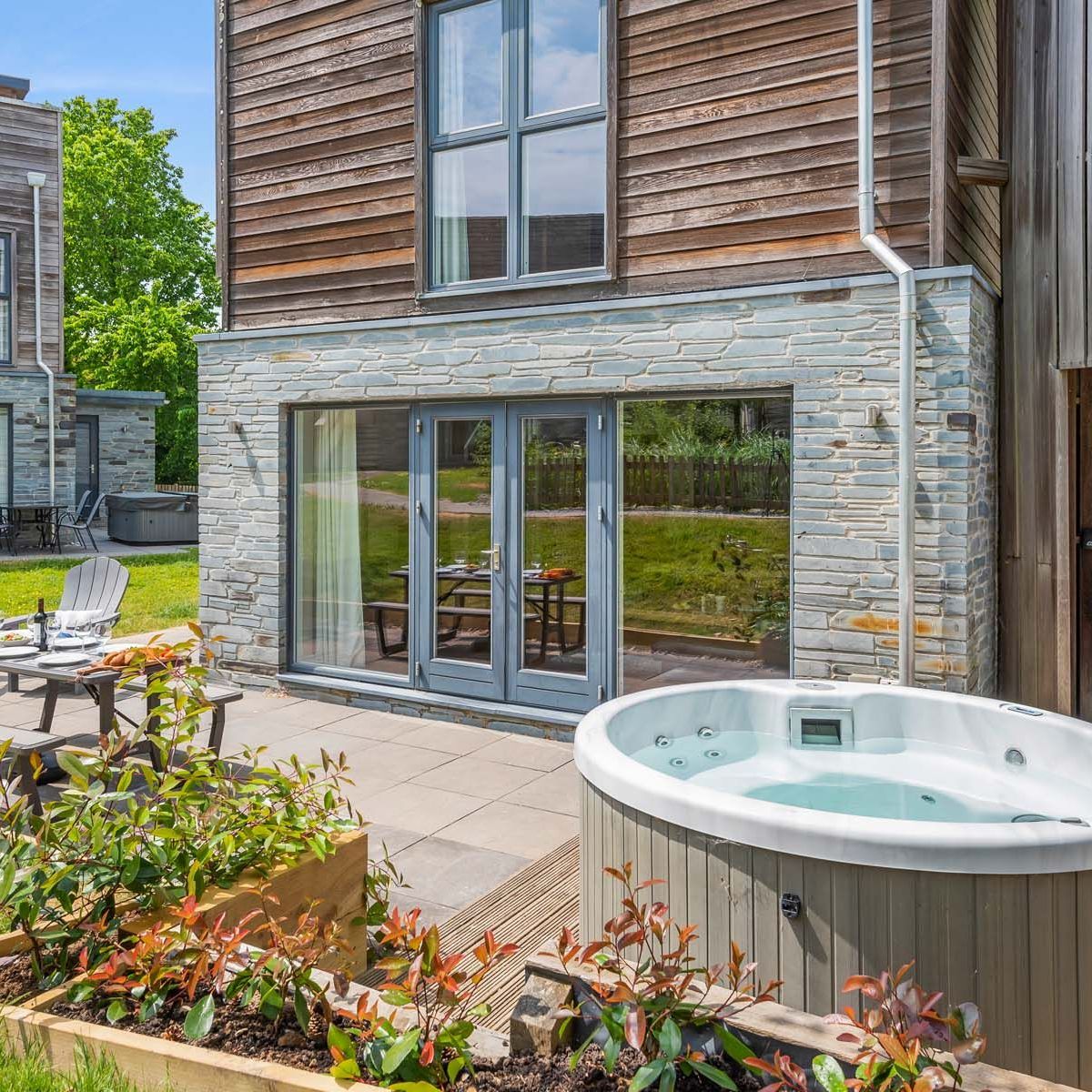 Modern house with patio, hot tub, outdoor dining area, and barbecue