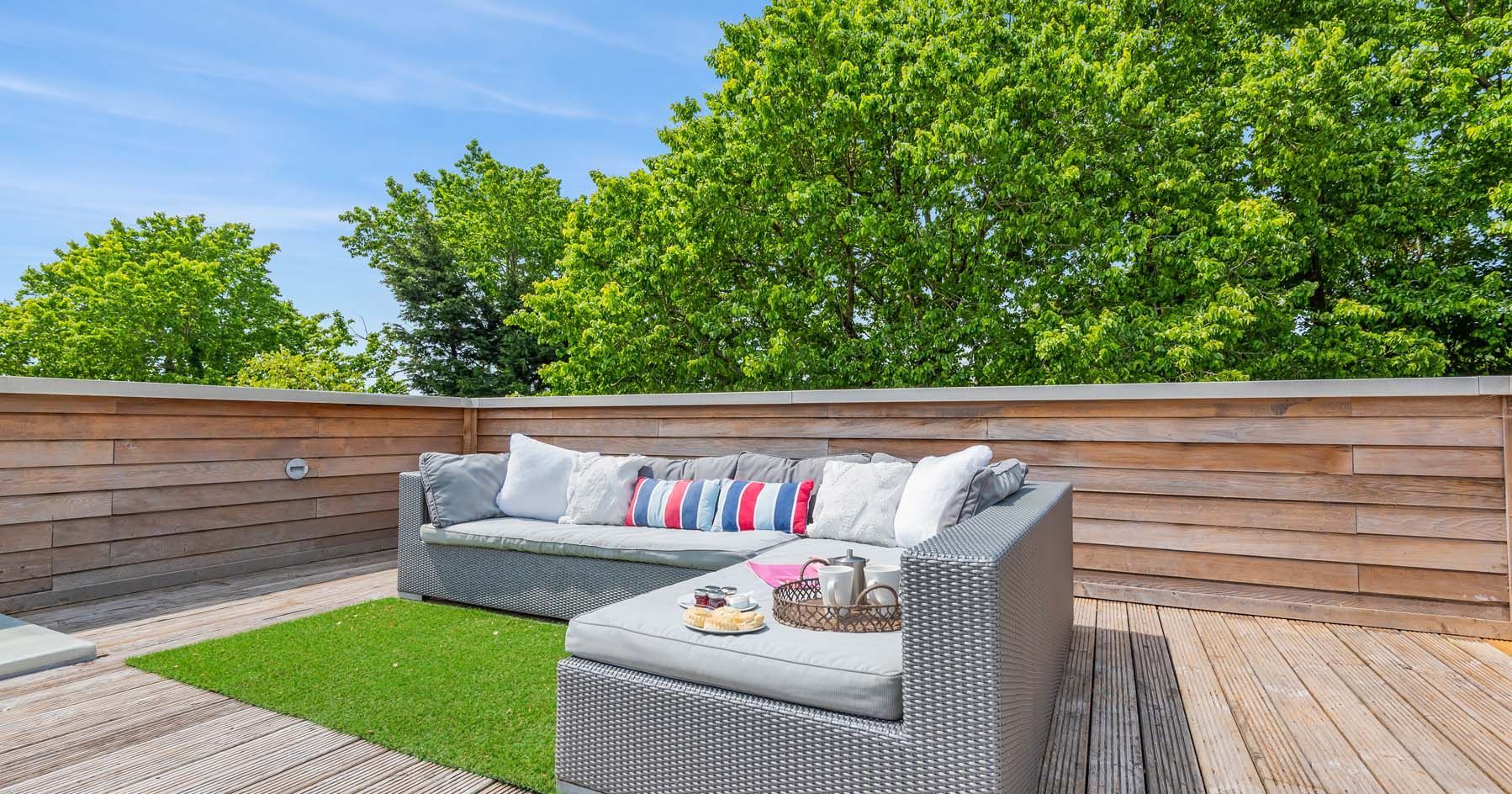 Modern outdoor terrace with sectional sofa and wooden deck