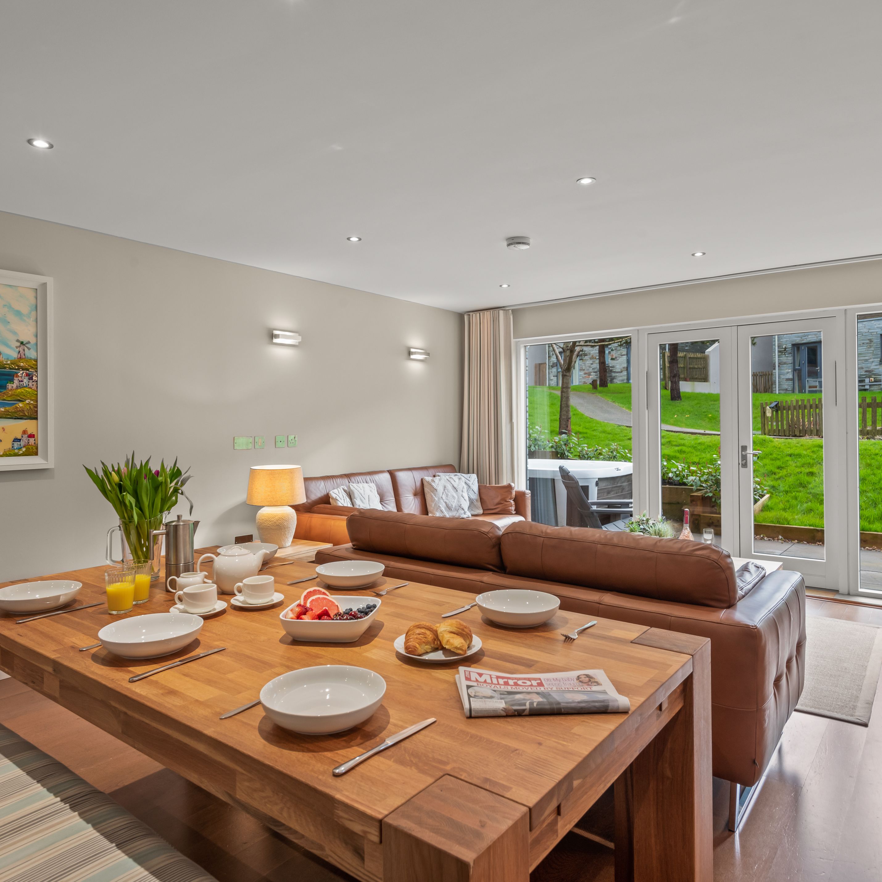 Modern open-plan dining and living area with large windows overlooking a grassy backyard.