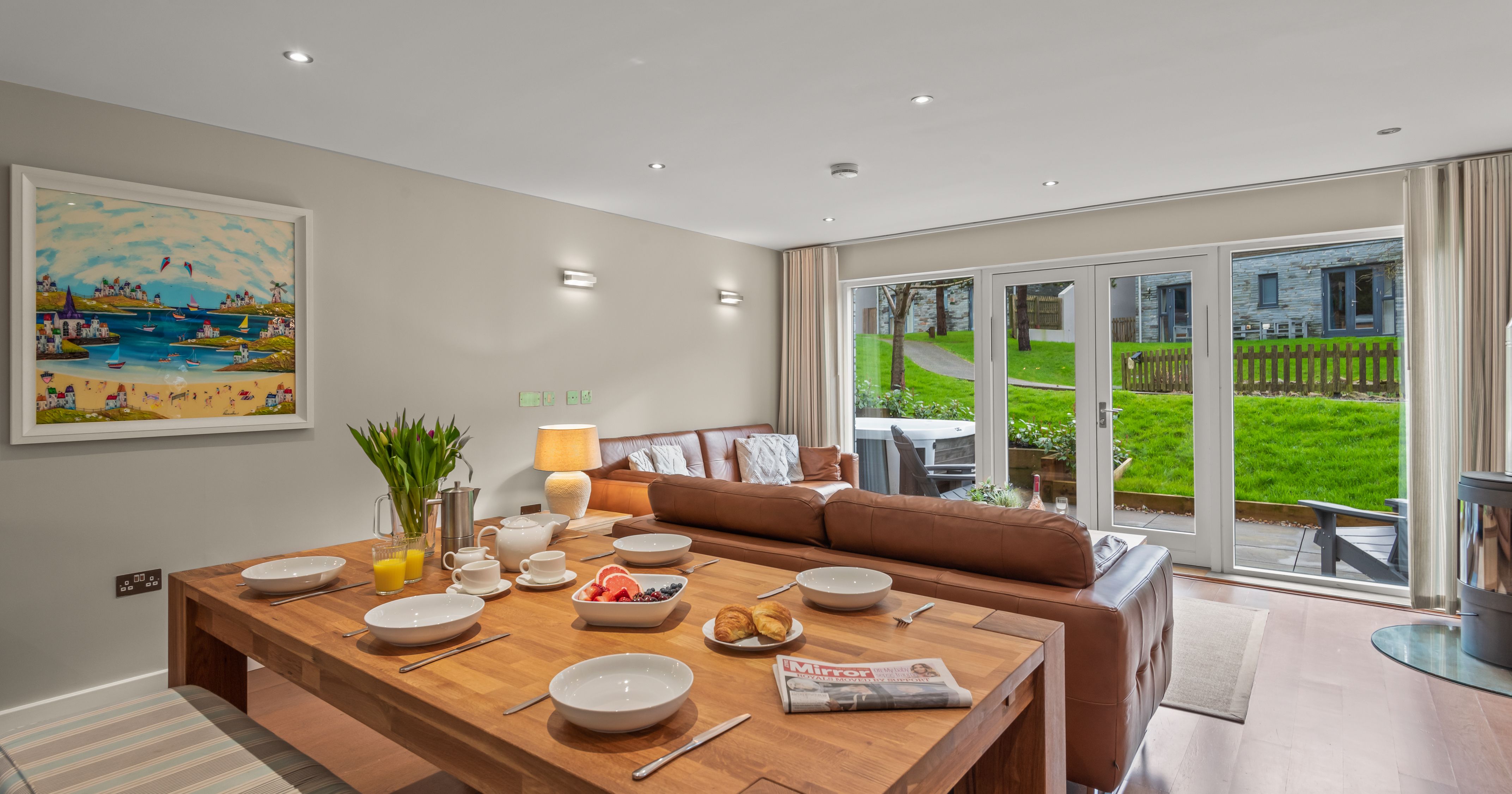 Modern open-plan dining and living area with large windows overlooking a grassy backyard.