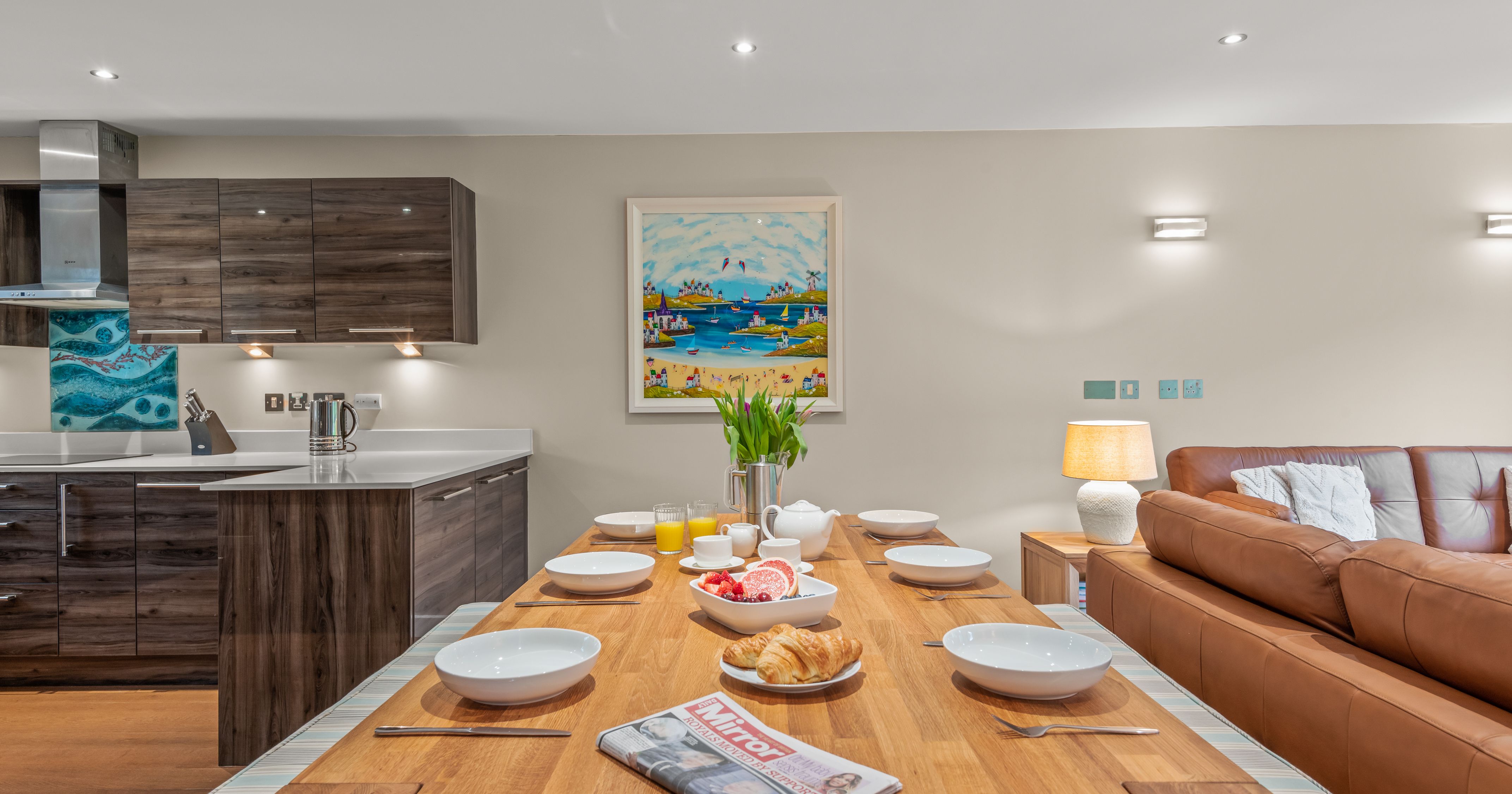 Modern open plan kitchen and dining area with breakfast set on wooden table.