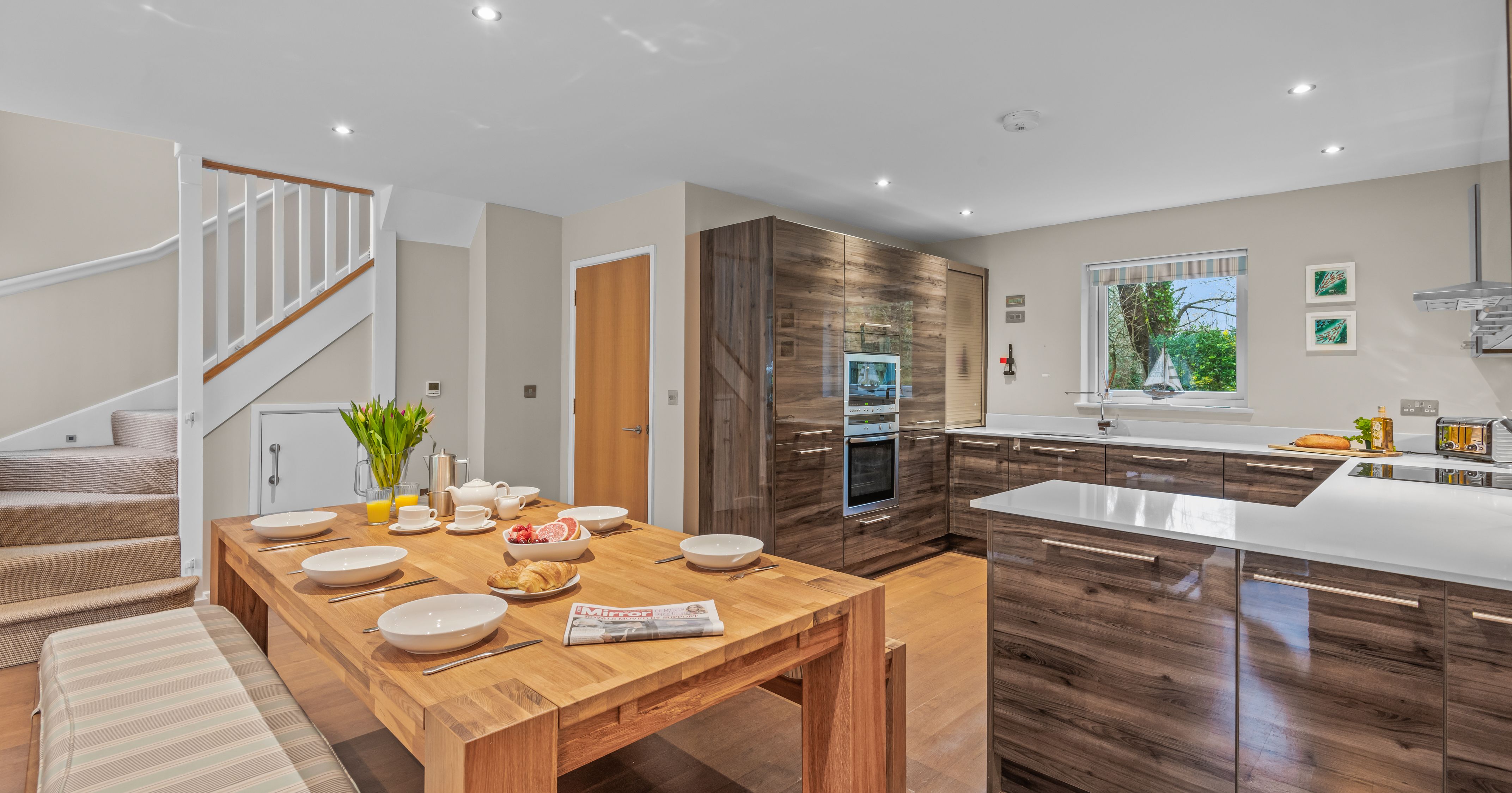 Modern kitchen and dining area with wooden cabinets and breakfast setup