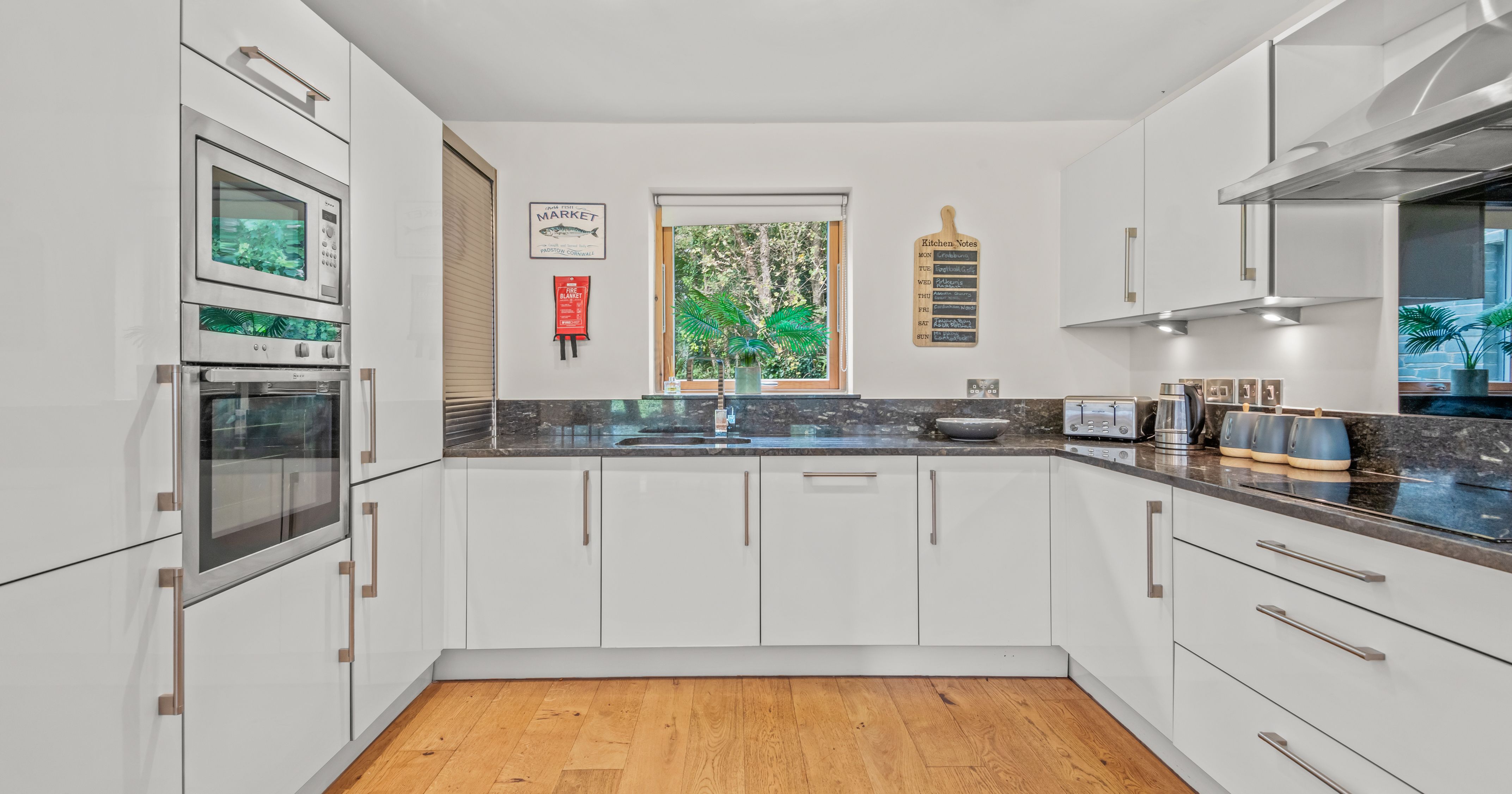 Modern white kitchen with built-in appliances and wooden flooring