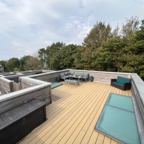 Modern rooftop terrace with outdoor seating and views of trees
