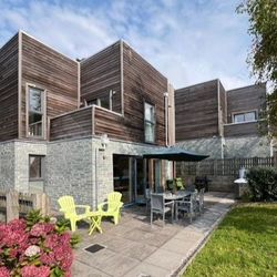 Modern house with wooden and stone exterior, patio seating and garden