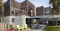 Modern house with wooden and stone exterior, patio seating and garden