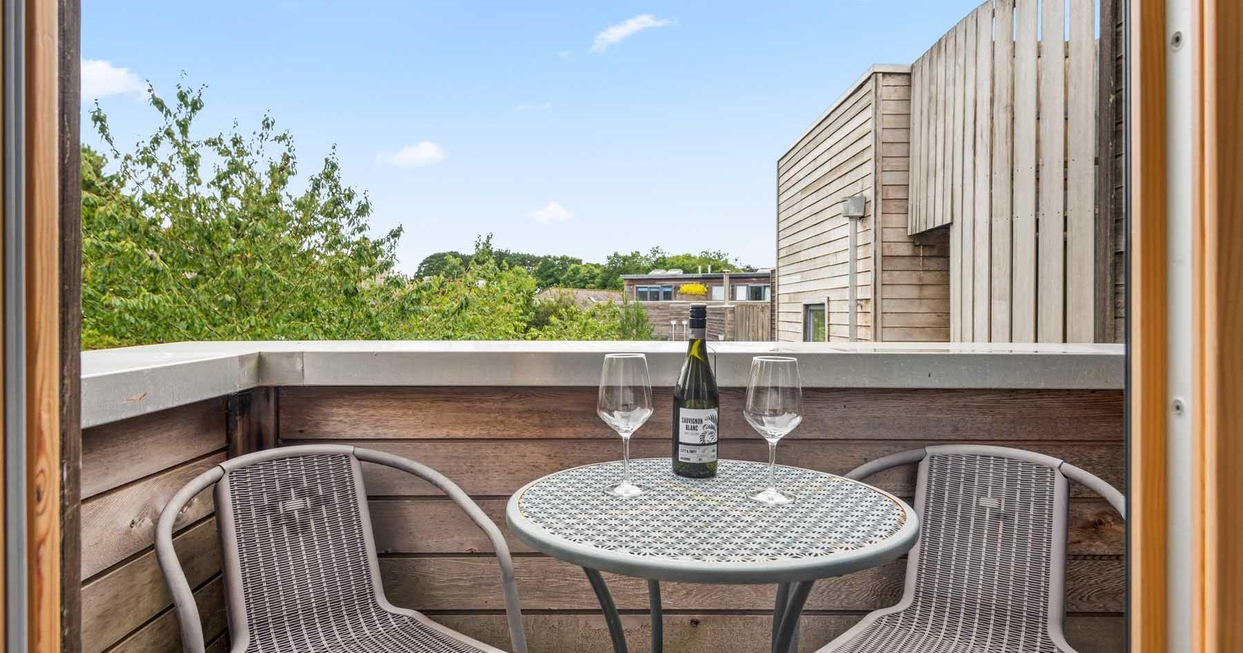 Small balcony with table, two chairs, wine bottle and glasses