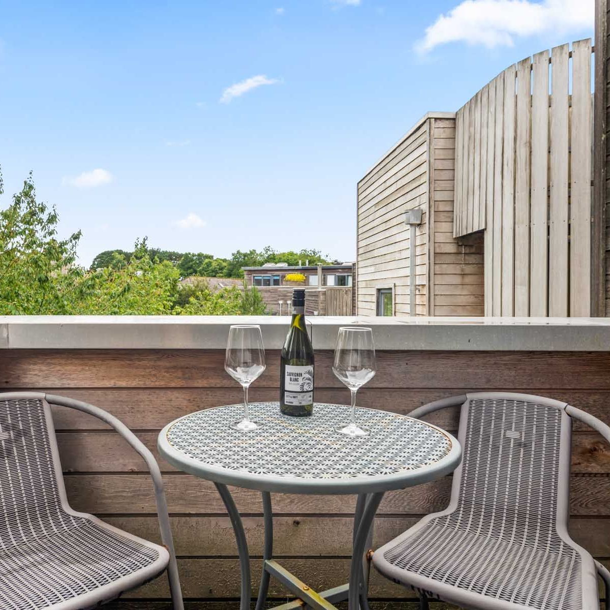 Small balcony with table, two chairs, wine bottle and glasses