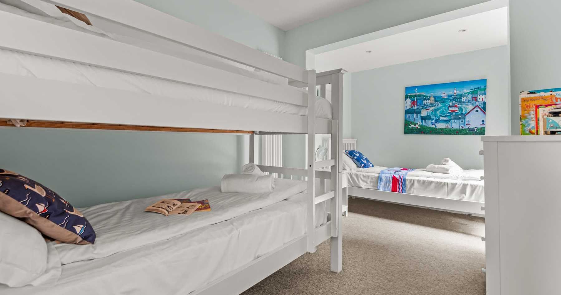 Bright bedroom with white bunk beds and a single bed