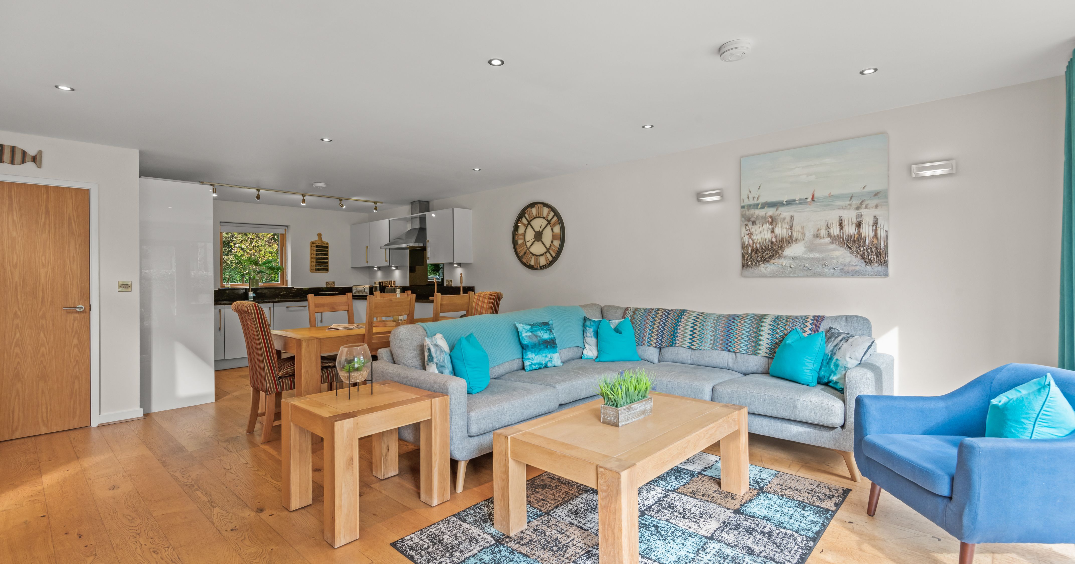 Modern open-plan living room and kitchen with wooden floors and blue accents