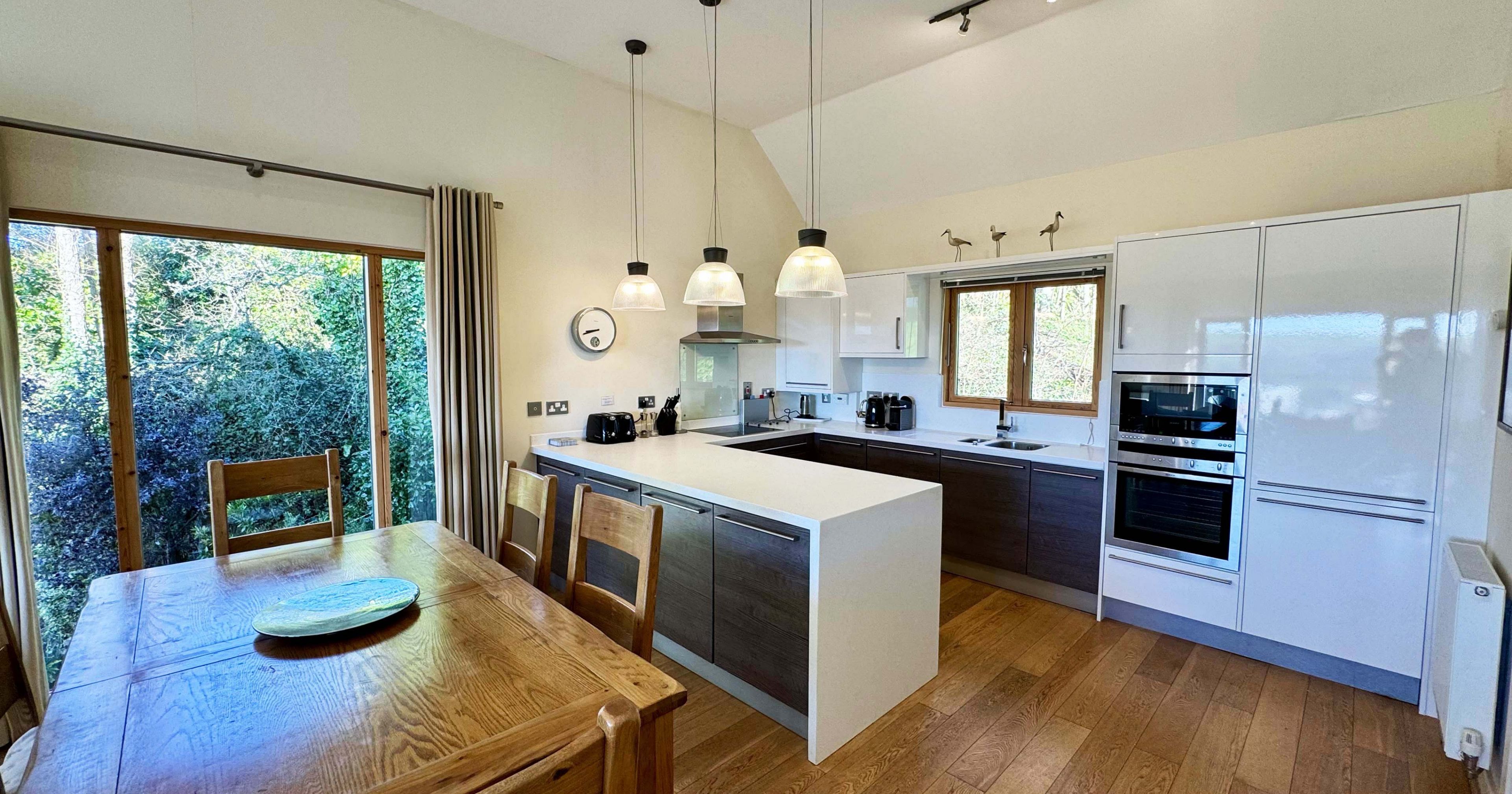 Modern kitchen with island and dining area featuring wooden table and chairs