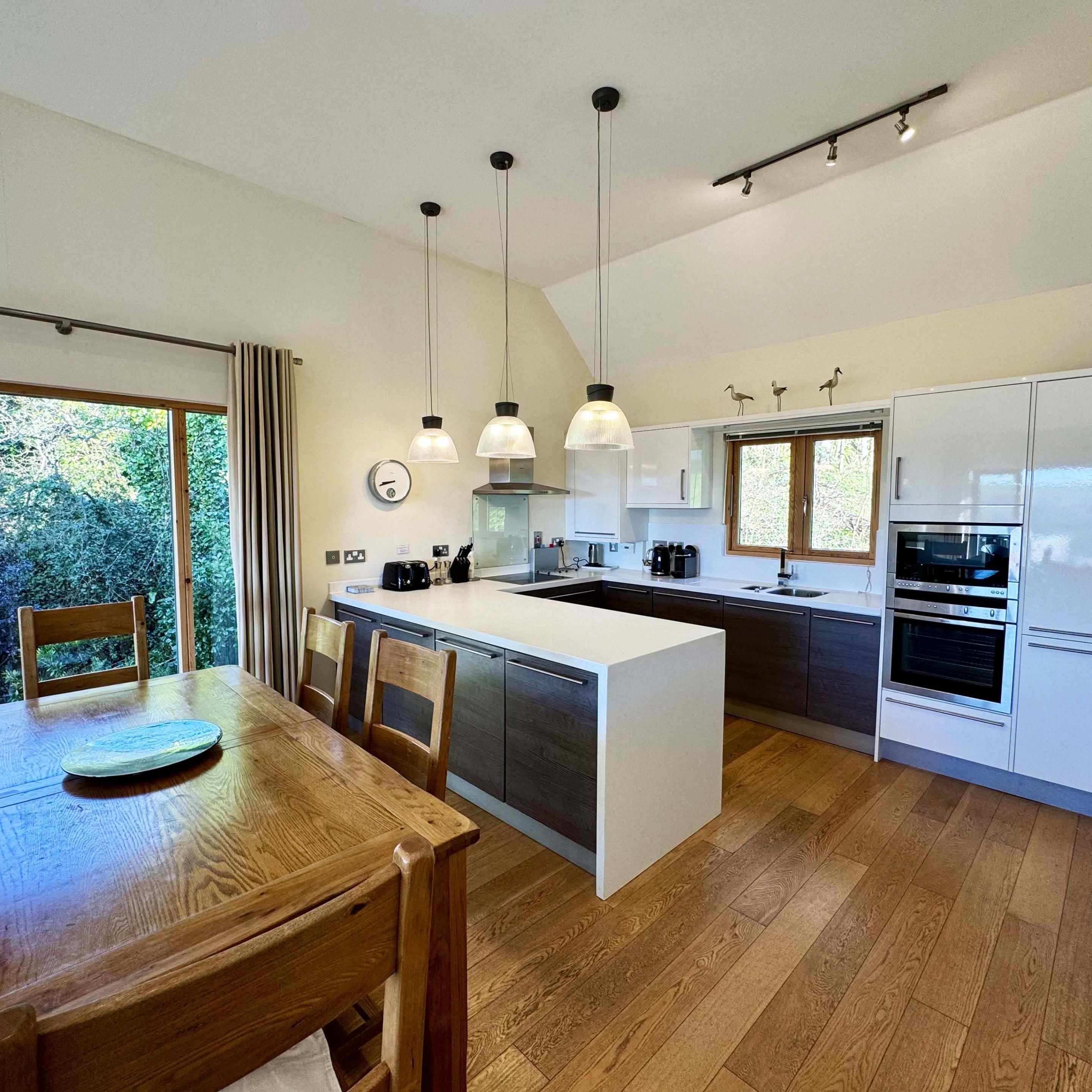 Modern kitchen with island and dining area featuring wooden table and chairs
