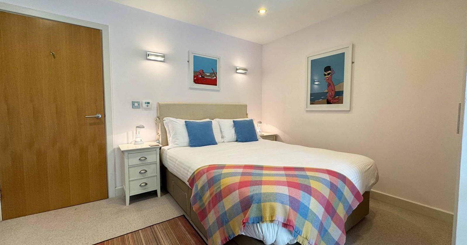 Modern bedroom with a double bed, colorful blanket, and wall art