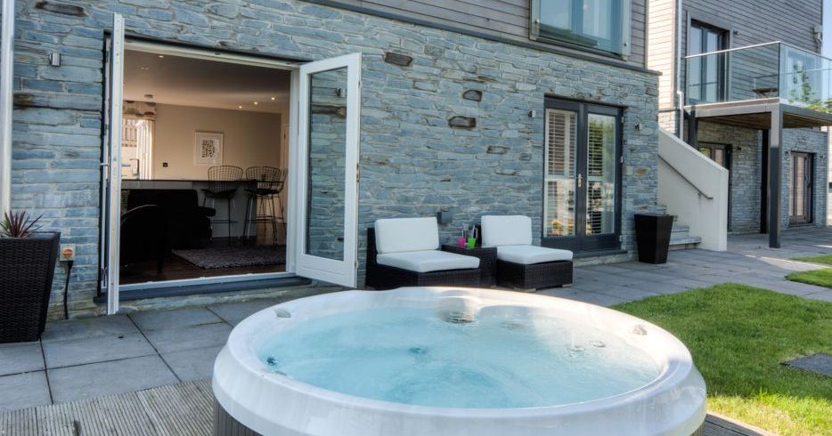 Modern house exterior with a hot tub and patio seating