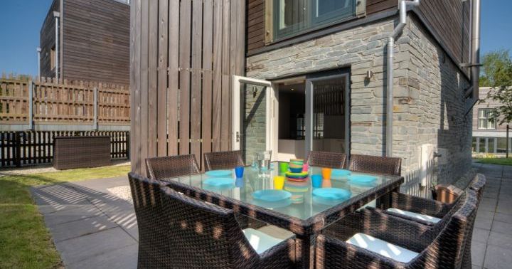 Outdoor patio dining area with glass table and wicker chairs