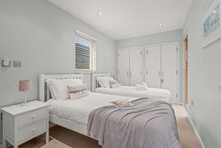 Modern bedroom with two single beds, white linens, and a nightstand.
