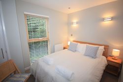Modern bedroom with double bed, wooden blinds, and bedside lamps