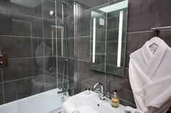 Modern bathroom with a robe hanging, illuminated mirror, and dark tile walls