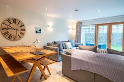 Modern open-plan living and dining area with grey sofas and wooden dining table.