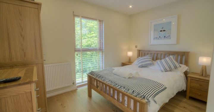 Bright bedroom with wooden furniture, double bed, and large window