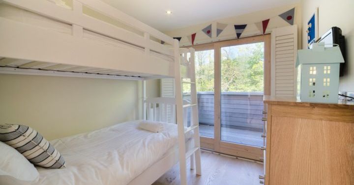 Children's bedroom with white bunk beds and large glass doors leading to a balcony