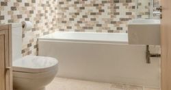 Modern bathroom with mosaic tile walls, bathtub, toilet, and sink