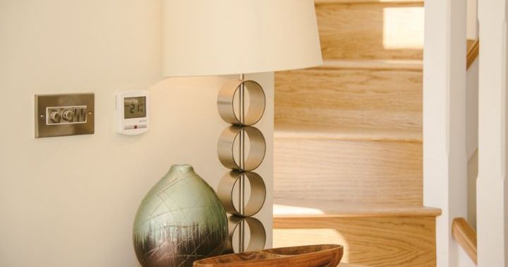 Modern lamp, vase, and wooden tray on a table near a staircase