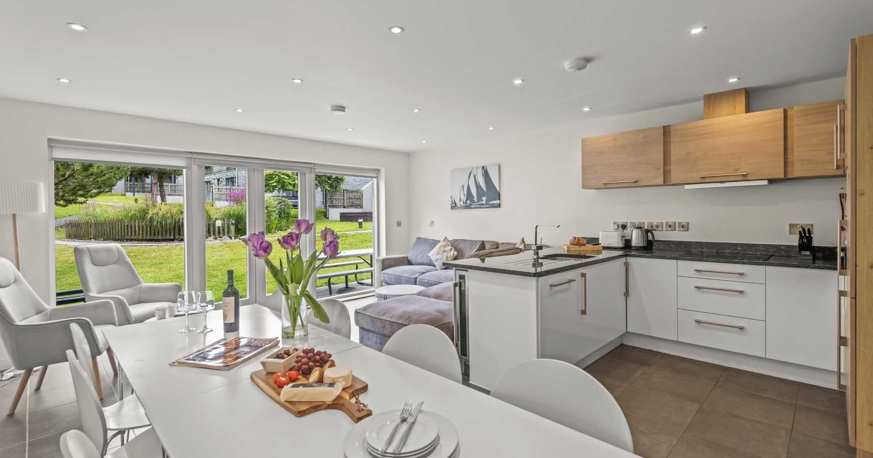 Modern open-plan kitchen and living room with large windows overlooking a green garden