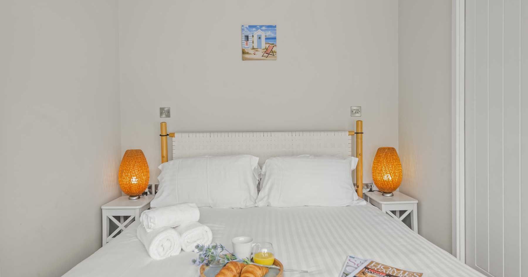 Cozy bedroom with white bedding, bedside lamps, and breakfast tray on bed