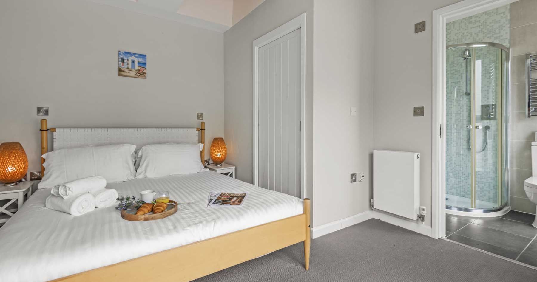 Modern bedroom with en-suite bathroom, neatly made bed, and breakfast tray