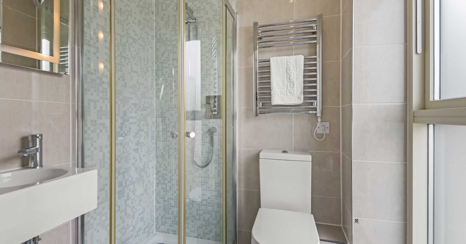 Modern bathroom with a glass shower, toilet, sink, and towel rack