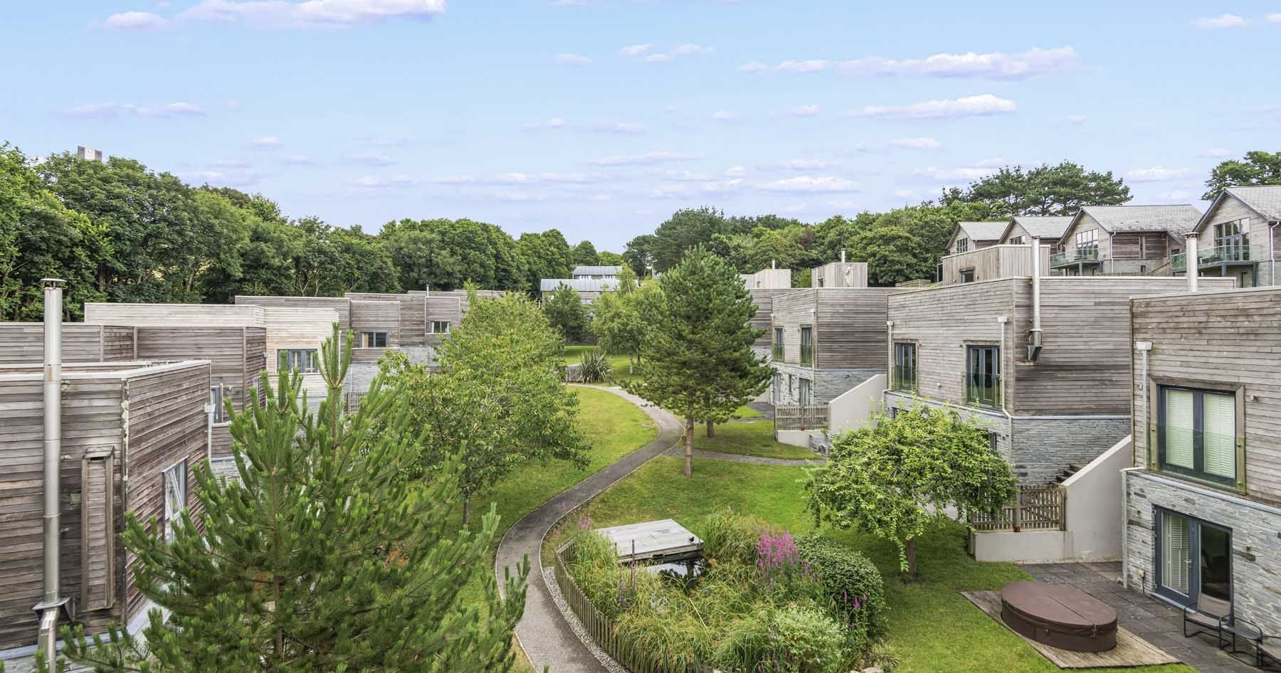 Modern wooden townhouses with green landscaping and walking paths.