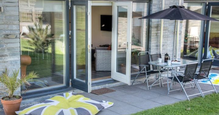 Modern patio with glass doors, outdoor dining set, umbrella, and a large cushion with a Union Jack design
