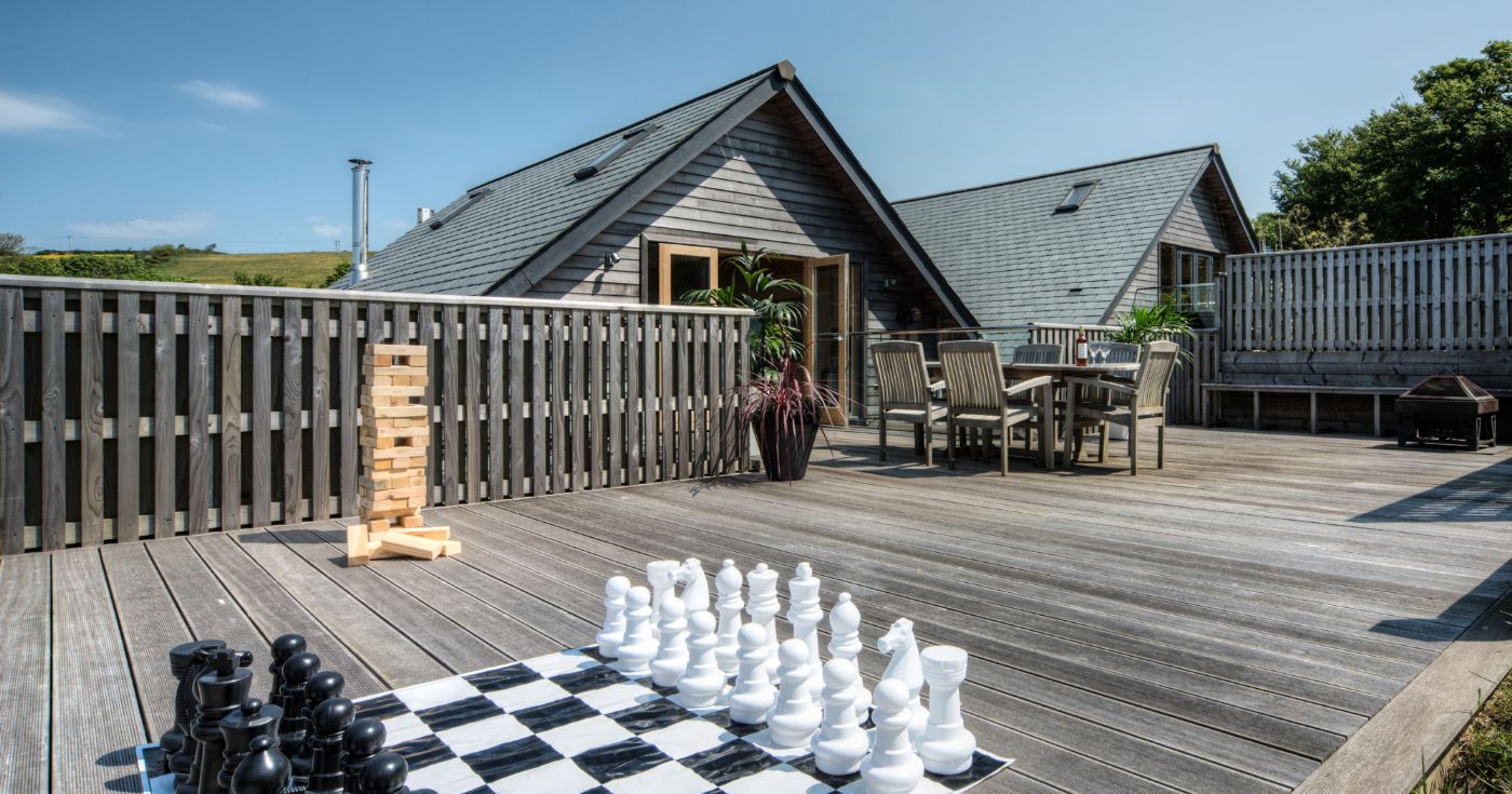 Spacious wooden deck with outdoor furniture, large chess set, and Jenga game