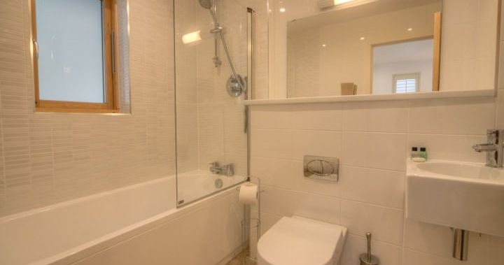 Modern bathroom with bathtub, toilet, sink, and large mirror